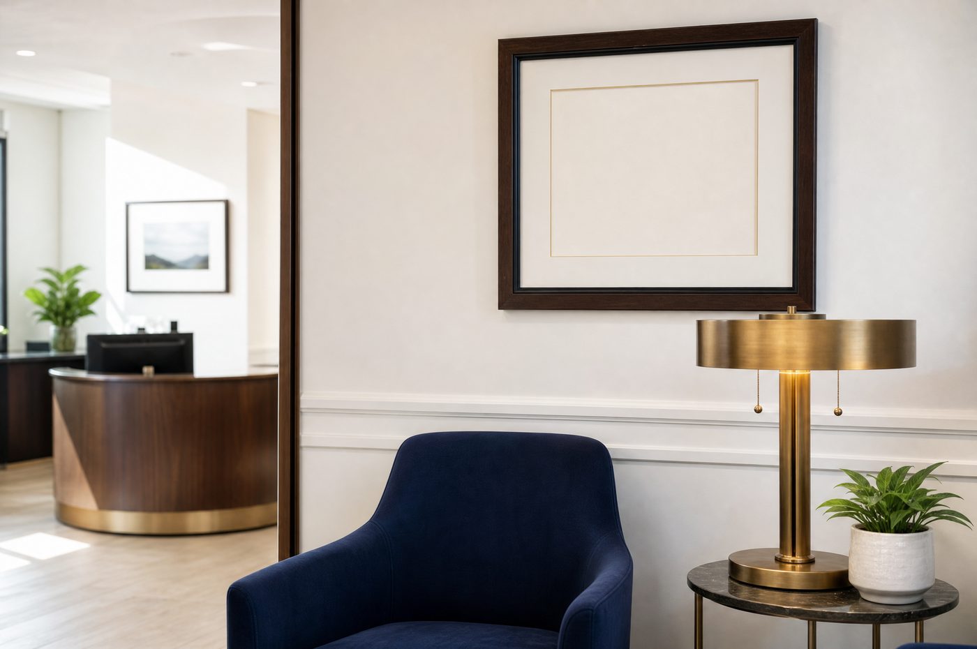 A calm office corner with a navy armchair, a brass lamp and a framed print